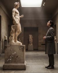 Visitor contemplating a classical marble nude sculpture in a museum, illustrating Renaissance body ideals and the human form in art history