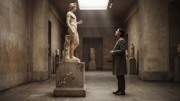 Visitante contemplando una escultura clásica de mármol desnuda en un museo, ilustrando los ideales corporales renacentistas y la forma humana en la historia del arte