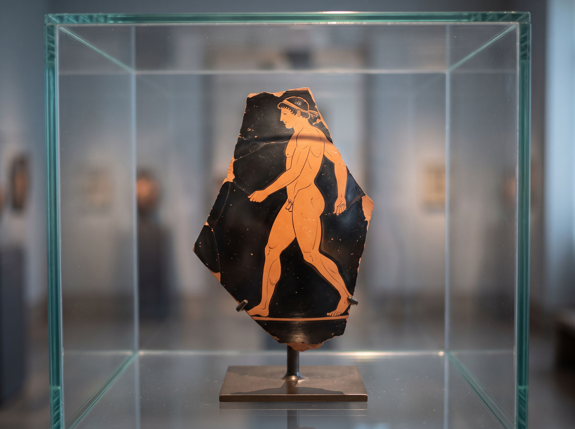 Detail of an Attic red-figure vase in a museum case showing an athlete figure