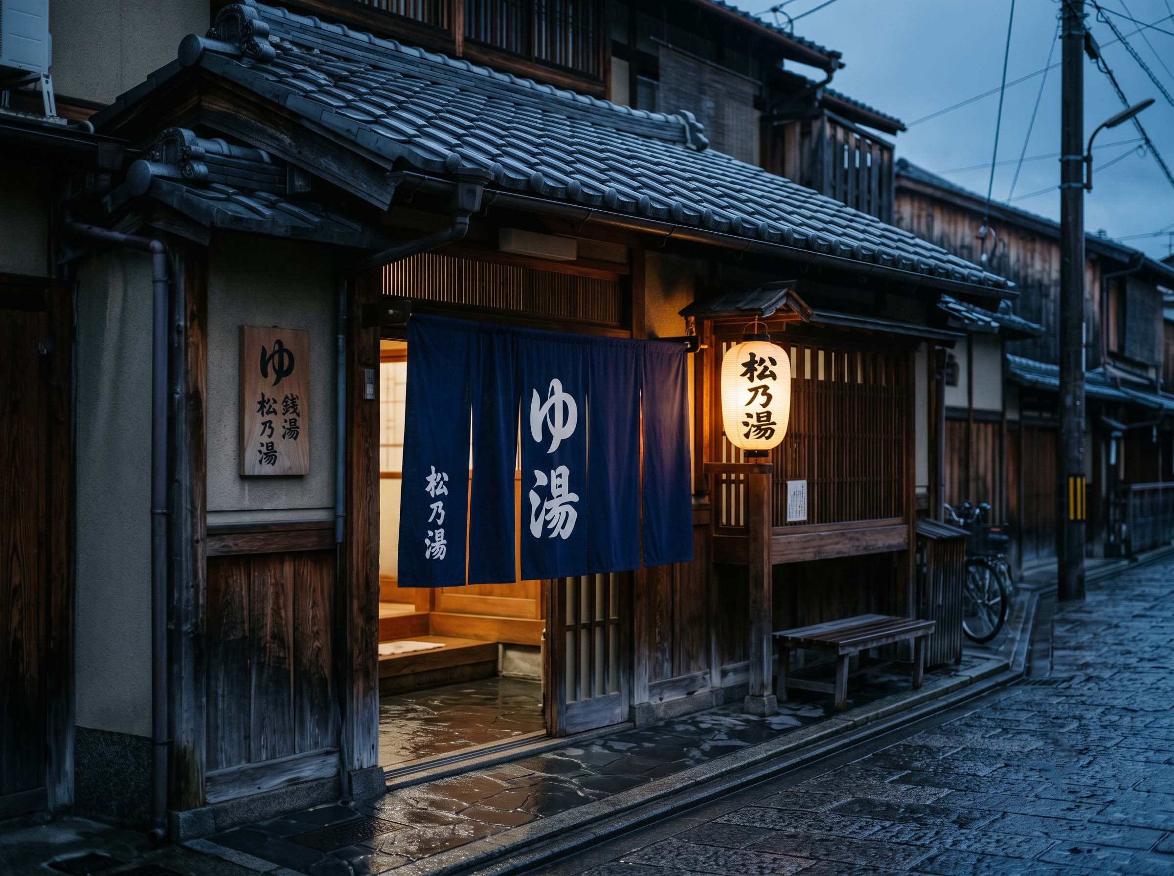 The tiled exterior and split entrance curtain of a traditional Japanese public bathhouse at dusk