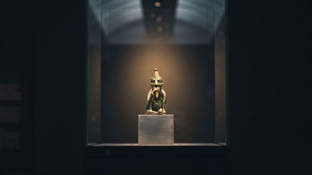 A small Viking Age bronze figurine lit in a museum vitrine, illustrating Norse mythology and the body