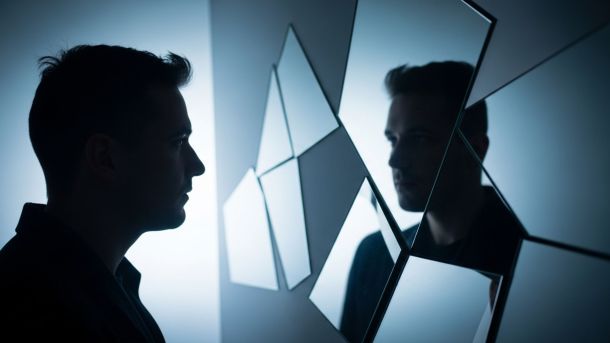Man viewing reflection in segmented mirrors illustrating perception versus reality