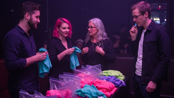 Hombres y mujeres en una fiesta de feromonas oliendo camisetas y conociéndose a través de un emparejamiento basado en el olor.