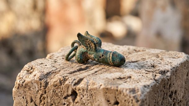Weathered Roman bronze protective charm on stone, symbol against the evil eye in ancient Rome