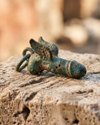 Weathered Roman bronze protective charm on stone, symbol against the evil eye in ancient Rome